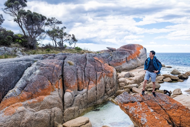 Free Photo asian male is posing in bay of fire in tasmania, australia