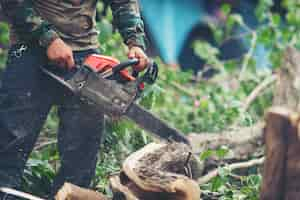 Free photo asian man cutting trees using an electrical chainsaw