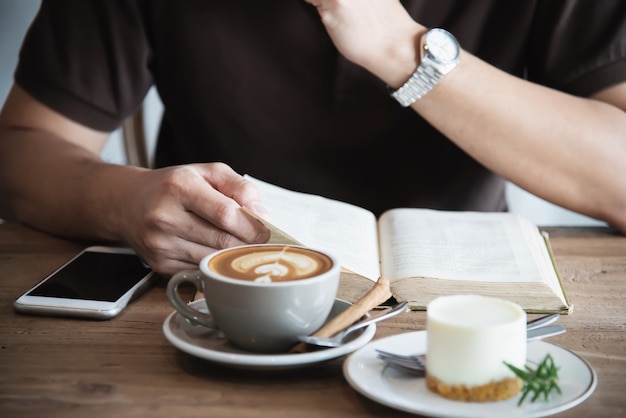 Asian man drinking a coffee and reading a book