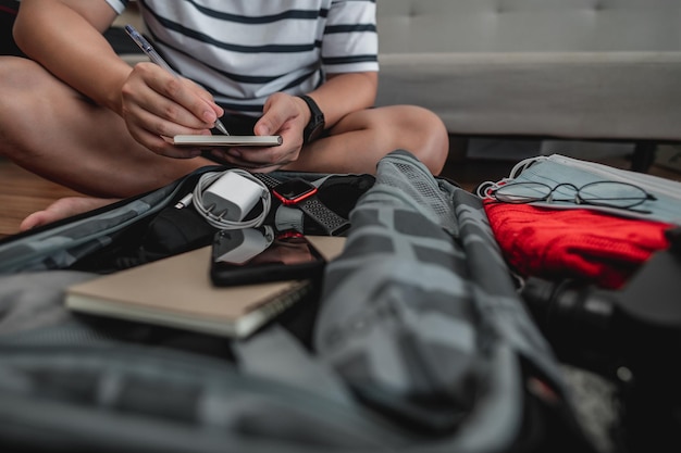 Free photo asian man is preparing clothes in suitcases he's choosing clothes travel documents the itinerary for a solo trip and check the checklist travel holiday and vacation concept