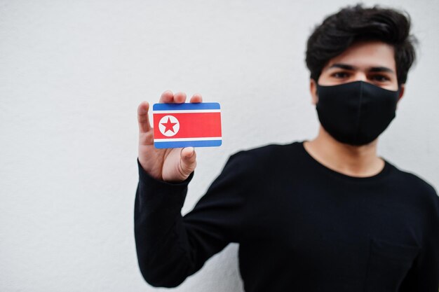 Asian man wear all black with face mask hold North Korea flag in hand isolated on white background Coronavirus country concept