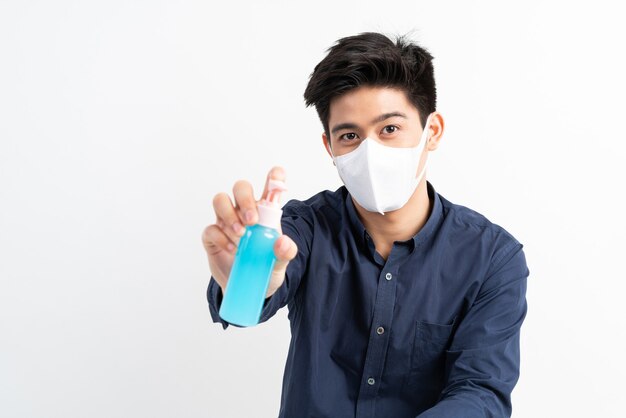 Asian man wearing Face Mask holding Alcohol for washing hands to protect Coronavirus covid-19 in quarantine room 