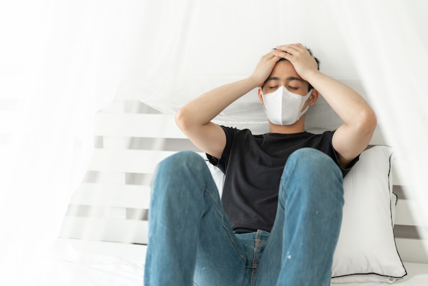 Free Photo asian man wearing face mask to protect  feeling sick headache and cough because of coronavirus covid-19 in quarantine room 