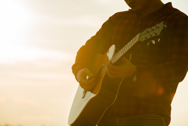 Free photo asian man with acoustic guitar during a sunset