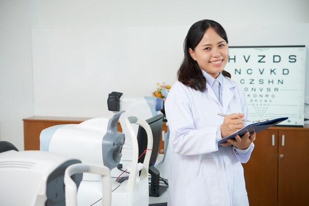 Asian ophtalmologist standing in examination room near eyesight testing machines