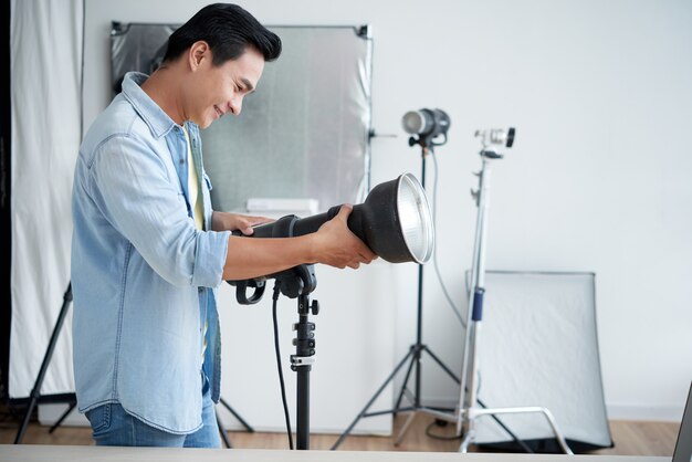 Asian photographer setting up lighting in professional studio