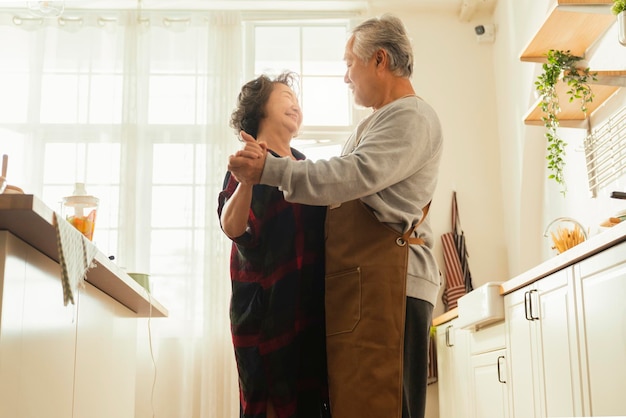 Free photo asian senior adult couple cooking healthy food together at home while dancing in the kitchen morning weekendhappiness asian old marry couple enjoy romantic cropped shot of a senior couple dancing