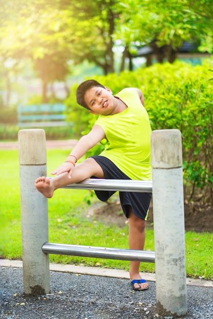 Asian sport boy stretching on iron bar in garden 