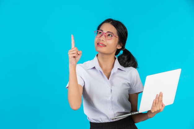 An Asian student girl holding her notebook on a blue .