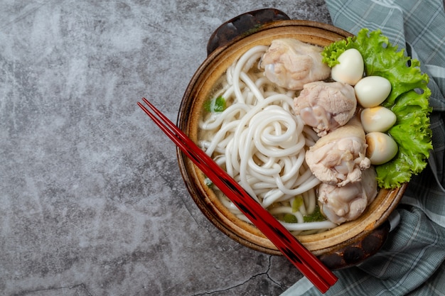 Asian style soup with noodles, pork and green onions closely in a bowl on the table.