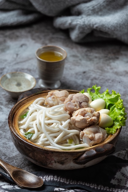 Asian style soup with noodles, pork and green onions closely in a bowl on the table.