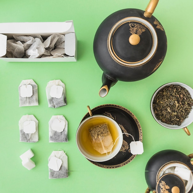 Asian tea set with herbal tea bags on green backdrop