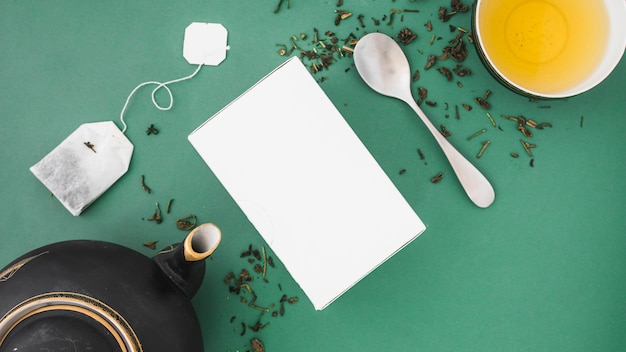 Asian teapot, teabag, spoon and herbal tea on colored backdrop