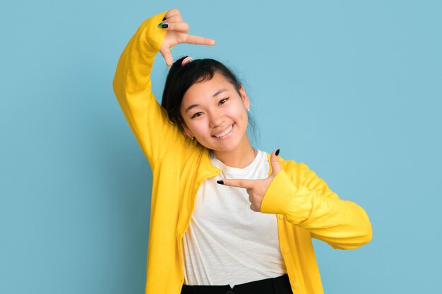 Asian teenager's portrait isolated on blue studio background