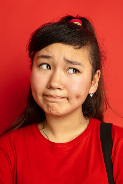 Asian teenager's portrait isolated on red  space