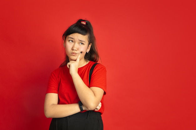 Asian teenager's portrait isolated on red  space