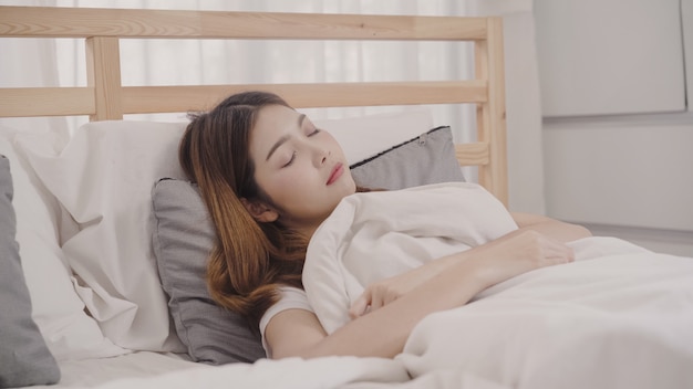 Asian woman dreaming while sleeping on bed in bedroom