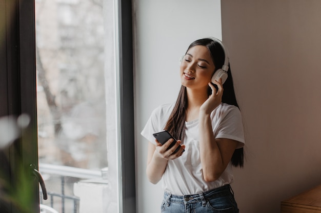 Asian woman enjoying music in headphones with eyes closed