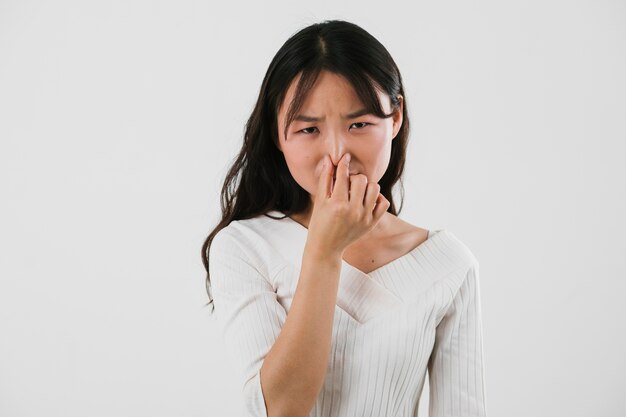 Asian woman holding her nose