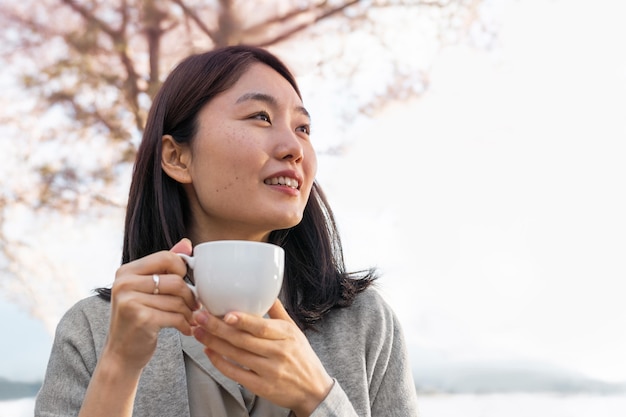 Asian woman relaxing outdoors next to a cherry tree