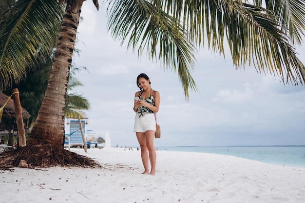 Asian woman talking on the phone at the beach