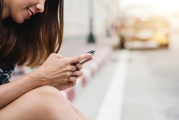 Asian woman tourist backpacker smiling and using smartphone traveling alone