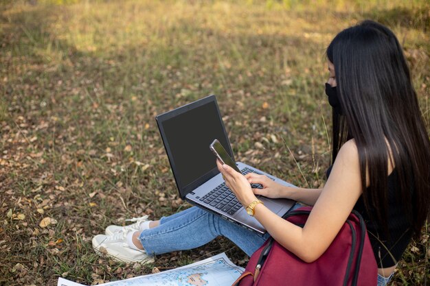 Asian woman tourist wearing face mask looking at laptop