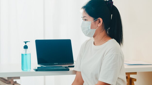 Asian woman using alcohol gel hand sanitizer wash hand before open tablet for protect coronavirus. Female push alcohol to clean for hygiene when social distancing stay at home and self quarantine time