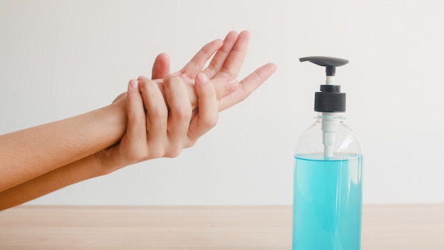 Asian woman using alcohol gel hand sanitizer wash hand for protect coronavirus. Female push alcohol bottle to clean hand for hygiene when social distancing stay at home and self quarantine time.