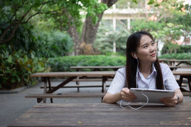 asian woman using tablet and listening to music