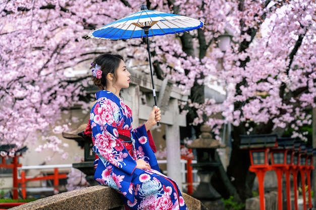 Free photo asian woman wearing japanese traditional kimono and cherry blossom in spring, kyoto temple in japan.