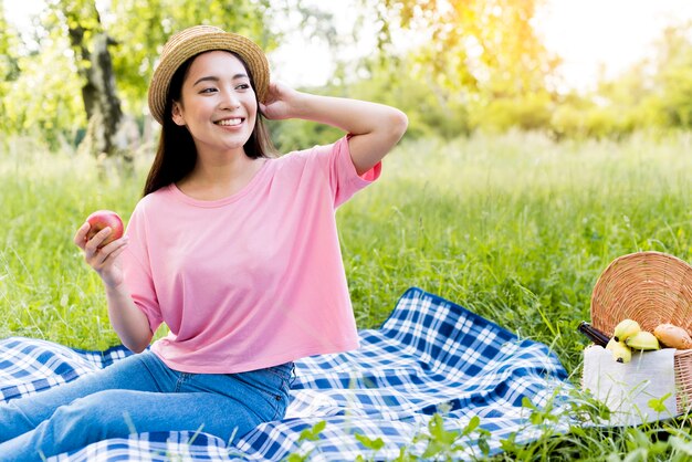 Asian woman with apple sitting on blanket