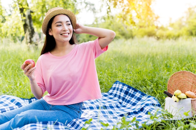 Asian woman with apple sitting on blanket