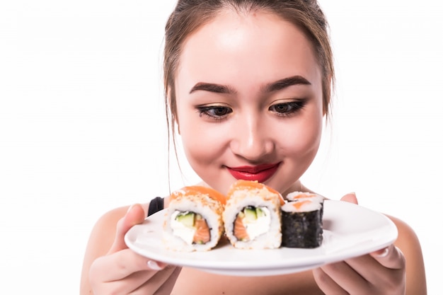 Free Photo asian woman with modest hairdo sits on the table eat sushi rolls smiling