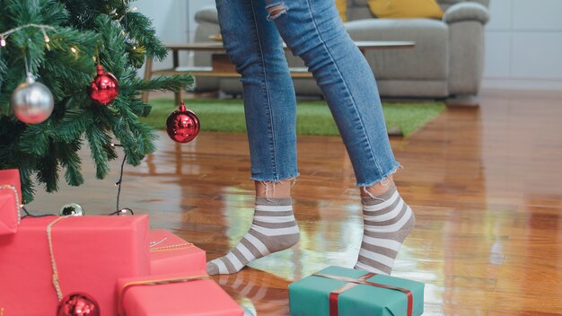 Asian women decorate Christmas tree at Christmas festival. Female teen stand celebrate xmas winter holidays in living room at home.