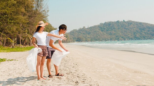 Asian young happy family activists collecting plastic waste on beach. Asia volunteers help to keep nature clean up and pick up garbage. Concept about environmental conservation pollution problems.