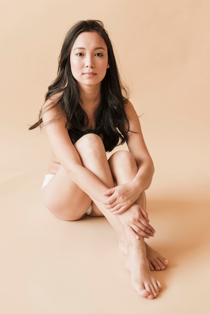 Free photo asian young woman in underwear sitting with legs crossed