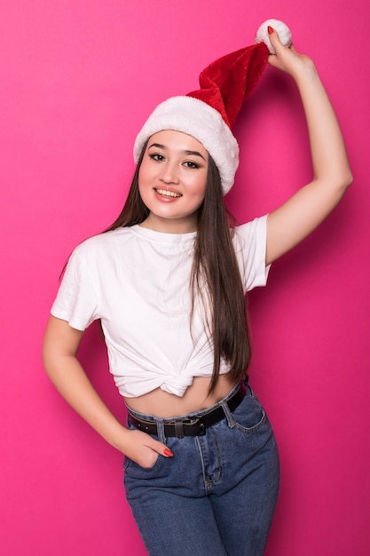 Free photo asian young woman wearing santa's hat isolated on pink wall