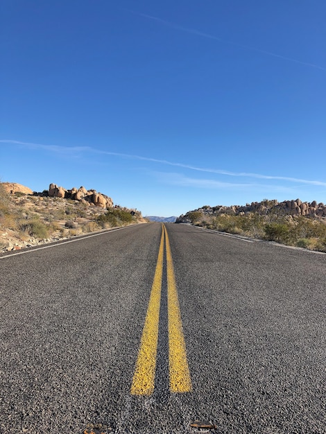 Asphalt road with yellow lines under a clear blue sky