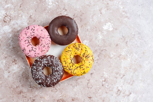 Assorted desserts with chocolate frosted, pink glazed and sprinkles.