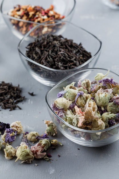 Assorted dried herbs in glass bowls close-up on a plaster surface