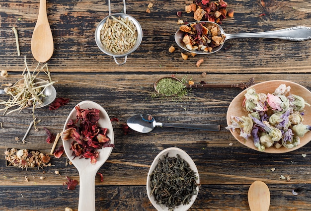 Assorted dried herbs in plastic jars on white surface, top view