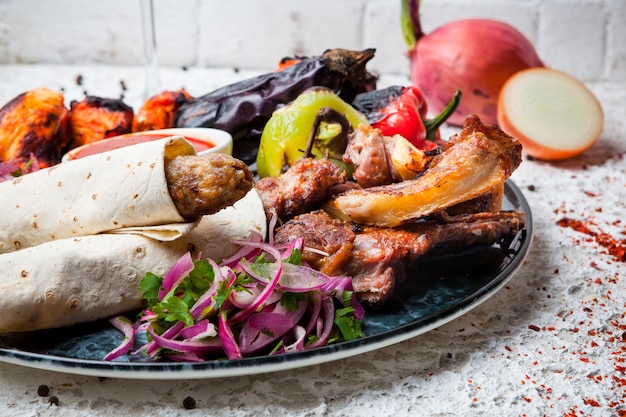 assorted kebab with fried vegetables and onion in round plate