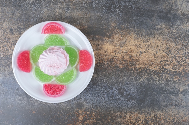 Assorted marmelades decoratively arranged around a cookie on a platter on wooden surface