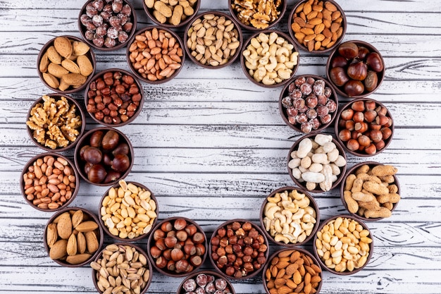 Free photo assorted nuts and dried fruits in a cycle shaped mini different bowls with pecan, pistachios, almond, peanut, top view