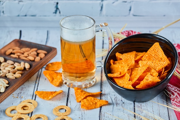 Assorted snacks, chips, and beer on blue table. Table for group of friends.