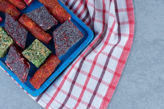 Assorted Turkish delight flavors on a wooden board, on the tea towel, on marble table. 