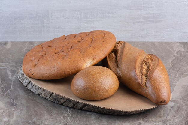 Assortment of bread loaves on a wooden board on marble background. High quality photo