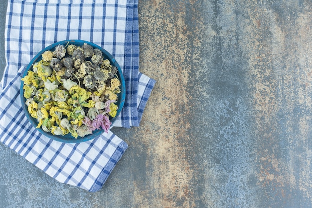 Assortment of dried organic flowers on blue plate.