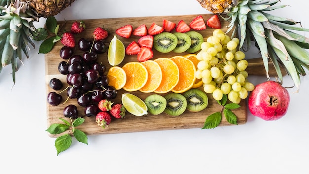 Assortment of fruits on chopping board over white background